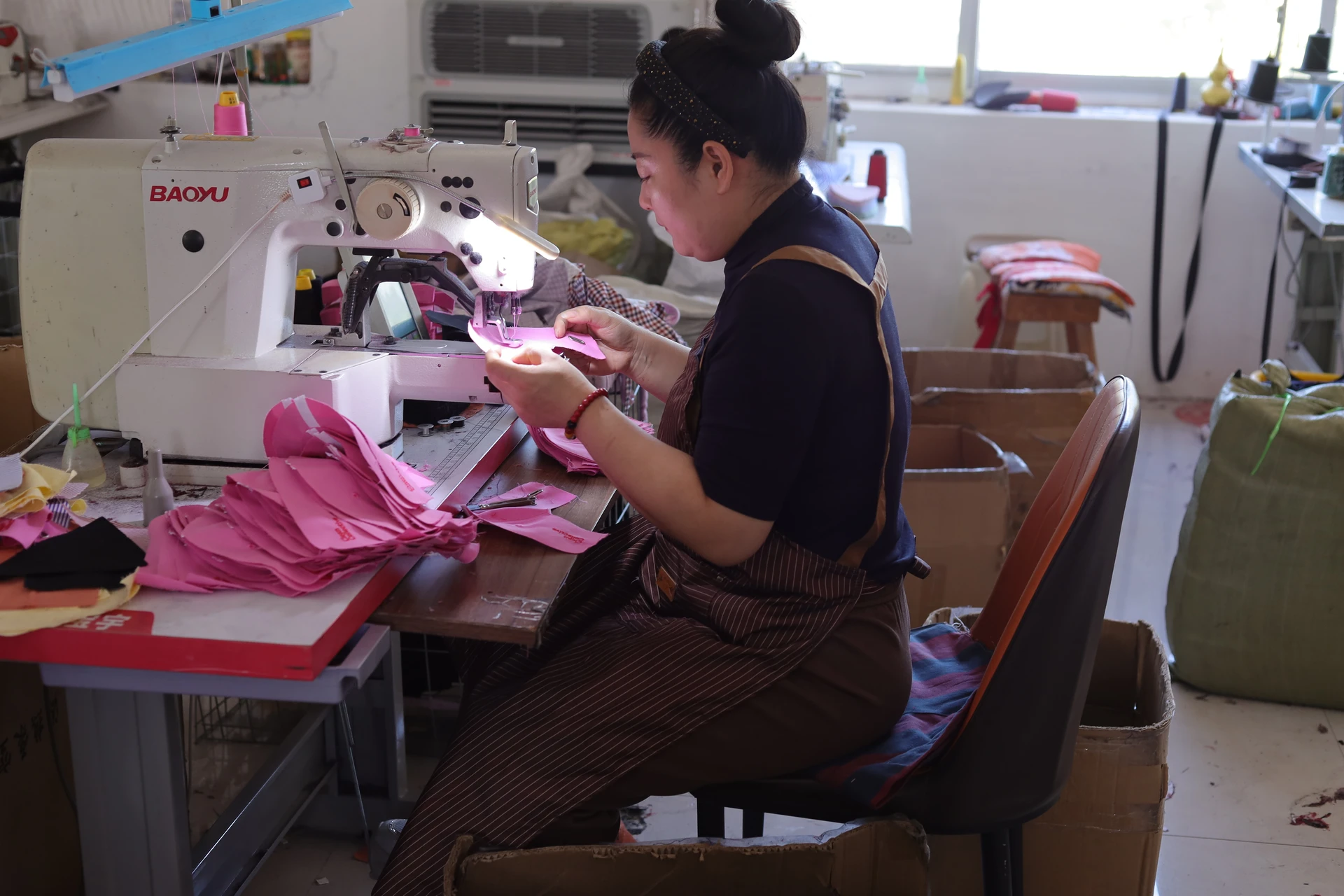 Caps Mill sewing operator assembling pink fabric panels on an industrial sewing machine