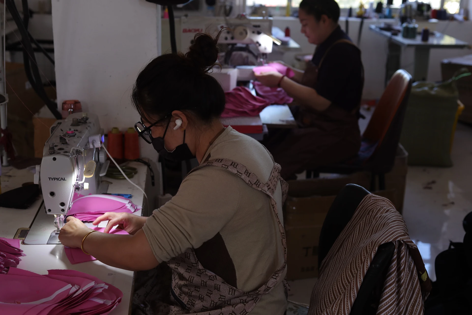 Pink cap panel being stitched at an industrial sewing machine in the Caps Mill workshop