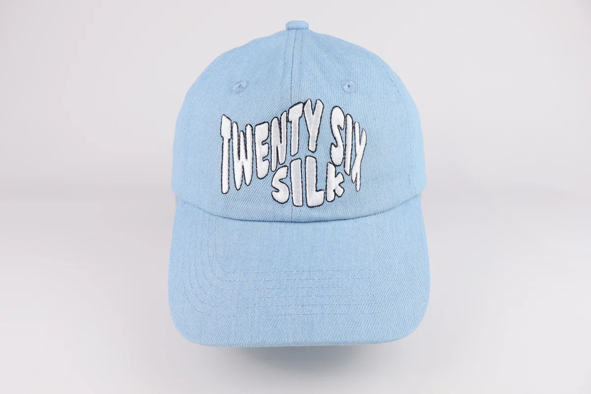 Light blue curved-brim cap with tall white outlined lettering embroidered on the front