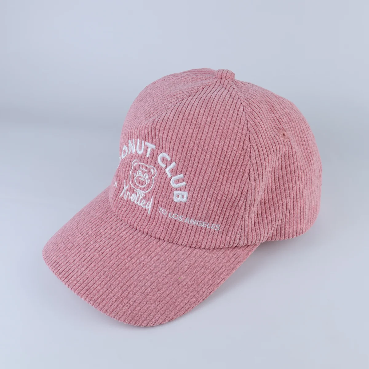 Pink corduroy cap with white curved front lettering and a curved visor