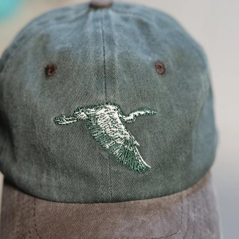 Close-up of green bird embroidery and faded cotton-look fabric
