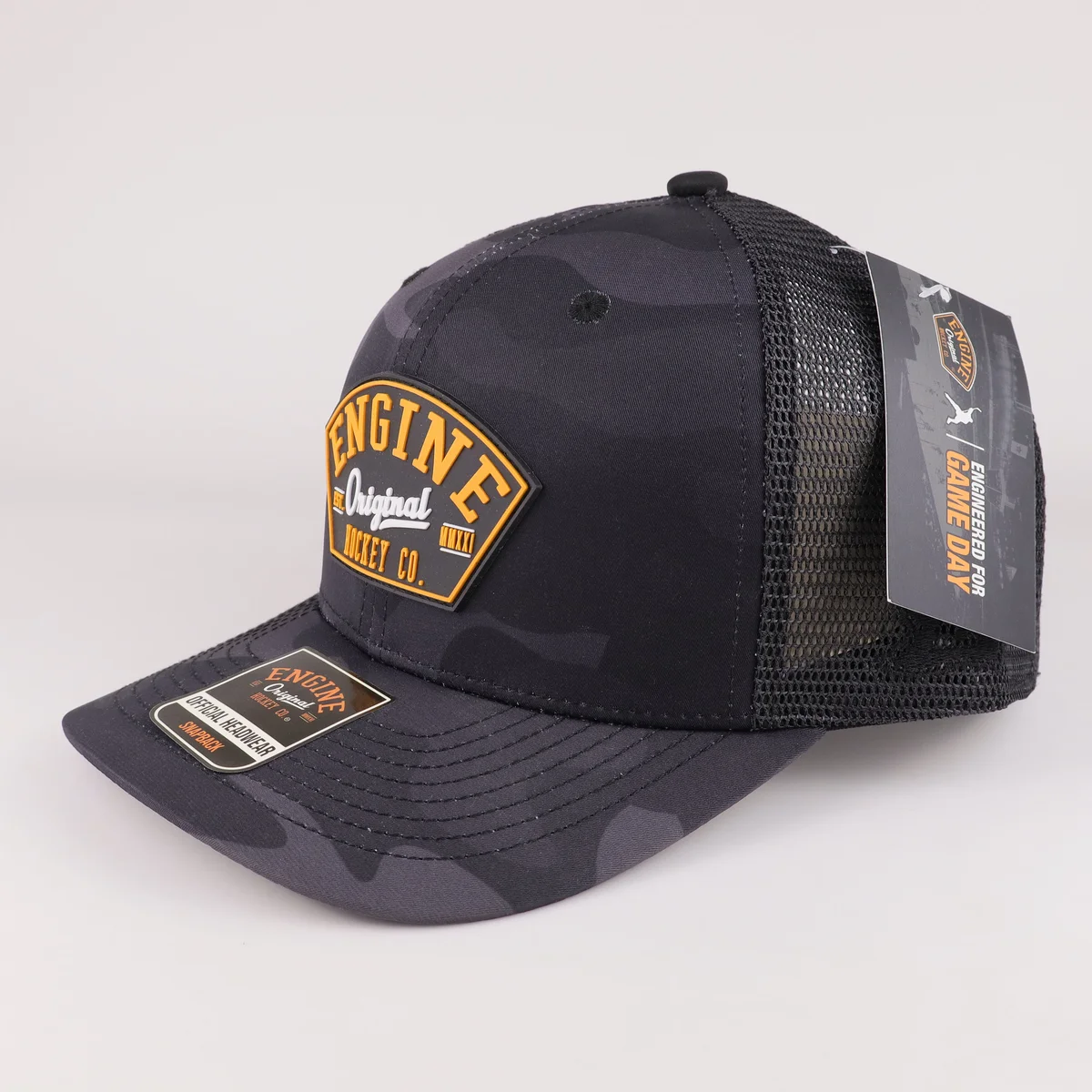 Angled front of black camouflage-pattern mesh trucker cap with orange raised logo patch
