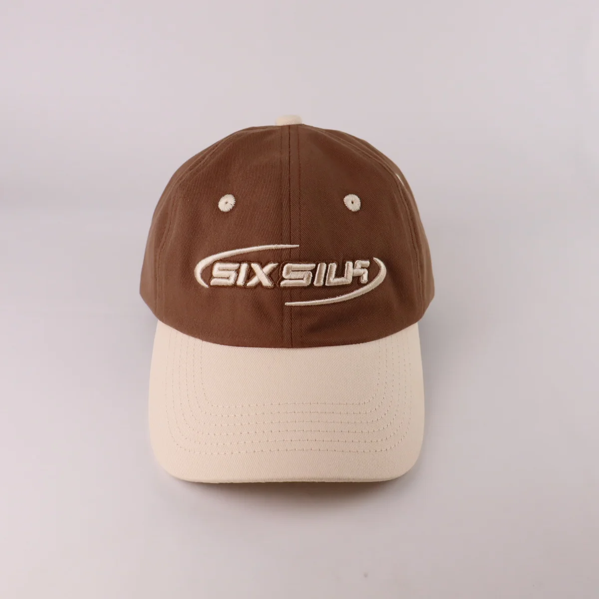 Front view of brown baseball cap with cream visor and matching off-white front embroidery