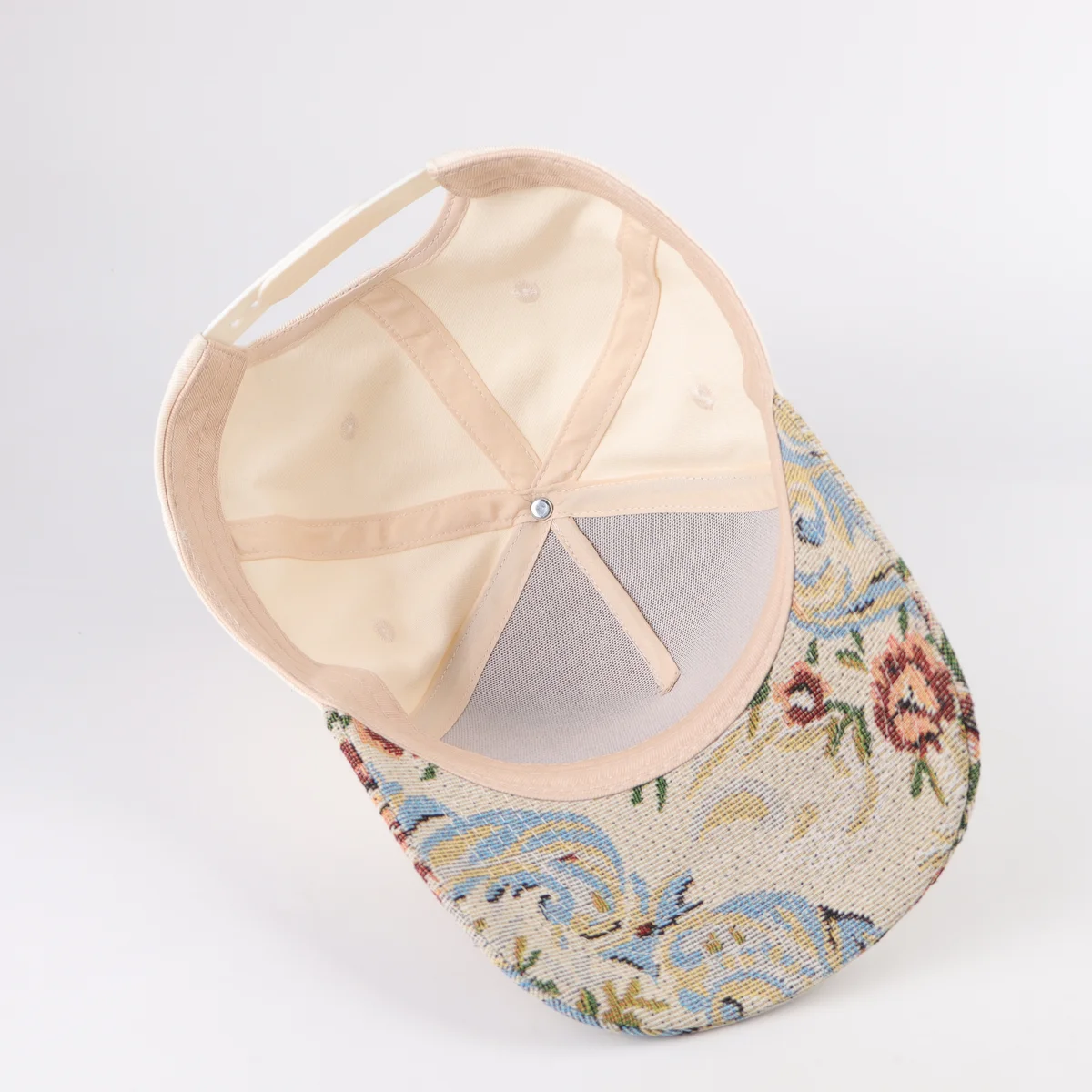 Interior of cream cap showing front panels and floral patterned visor underside