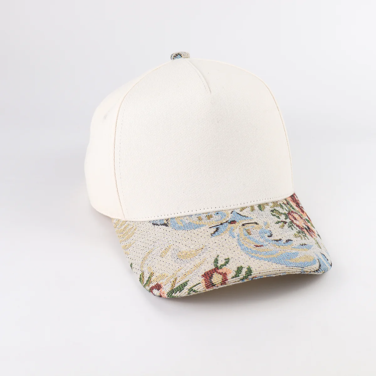 Three-quarter front angle of cream crown cap with multicolor patterned visor