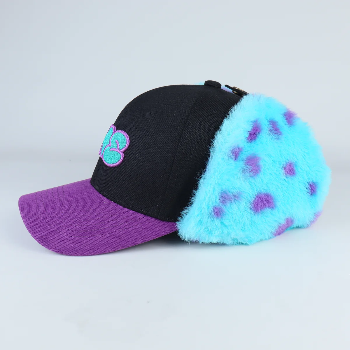 Side angle of black cap with purple brim and bright turquoise faux-fur spotted panels